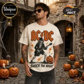 AC/DC High Voltage Halloween off-white t-shirt featuring a skeleton playing a guitar with lightning and pumpkin graphics.