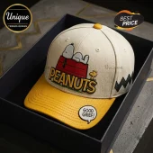 Peanuts Snoopy Cream Yellow Baseball Cap featuring Snoopy on his red doghouse with Woodstock and Good Grief text.