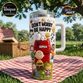 Snoopy and Friends Don't Worry Be Happy 3D tumbler with cartoon characters, a red doghouse, and custom name tag on a table.